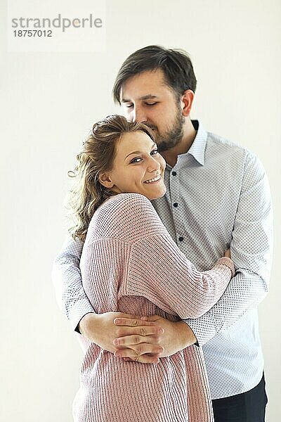 Seitenansicht des Inhalts liebendes Paar sanft umarmt auf weißem Hintergrund zu Hause