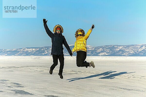 Ein glückliches Paar springt auf dem gefrorenen Baikalsee. Transparentes Eis. Reisen im Winter  aktive Erholung  Sport