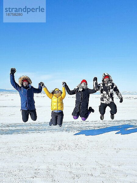 Gruppe von glücklichen Touristen Freunde springen auf dem Hintergrund der Eis Wintersee Baikal am sonnigen Tag. Winter Baikalsee  Russland. Konzept der Freiheit  Reisen und Glück