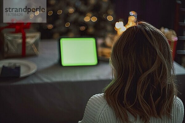 Glückliche junge Frau  die einen Cocktail trinkt und sich mit Freunden über einen virtuellen Zoom Videoanruf unterhält  um eine Neujahrsparty in einem Online Konferenz Chat auf einem Computer zu Hause zu feiern