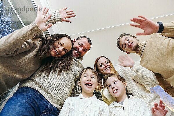 Blick von unten auf glückliche große kaukasische Familie mit vielen Kindern  die ein Selfiefoto zu Hause machen  Eltern mit Kindern  die mit der Kamera winken und Spaß haben  während sie zusammen ein Selfiefoto machen