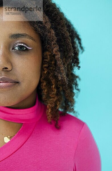 Dreamy junge schöne afroamerikanische Frau mit hellen Augenlinie trägt rosa Bodysuit über blaue Wand  schaut mit glücklichen Ausdruck
