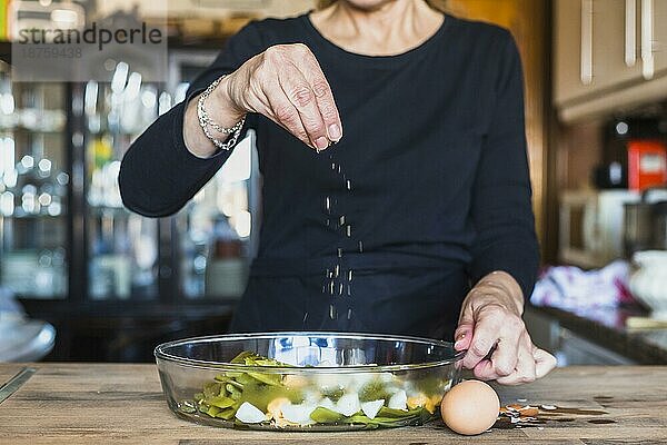 Ernte Hände ältere Frau bestreuen Gericht Salz. Foto mit hoher Auflösung