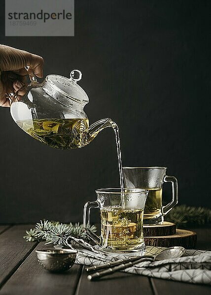 Vorderansicht Hand gießt Tee Glas mit Teekanne. Schönes Foto