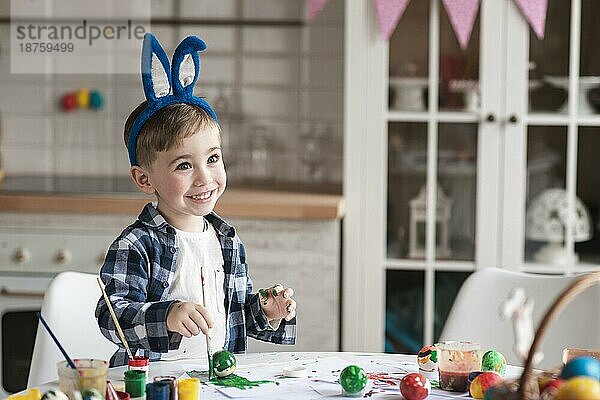 Porträt glücklicher kleiner Junge beim Bemalen von Ostereiern