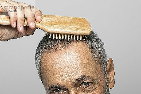 Nahaufnahme älterer Mann beim Bürsten der Haare