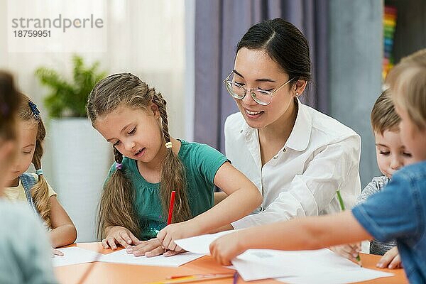 Junge Lehrerin hilft ihren Schülern in der Klasse. Foto mit hoher Auflösung