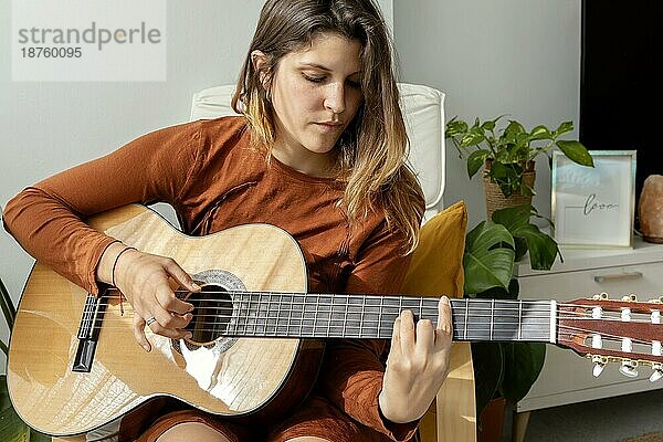 Frau zu Hause spielt Gitarre