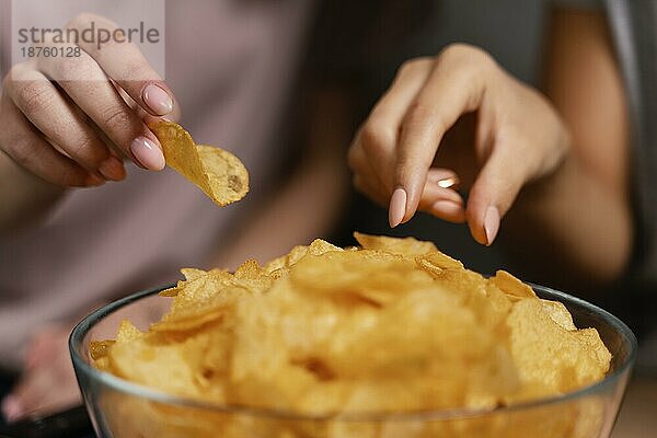 Frauen auf der Couch  die fernsehen und Chips essen  Nahaufnahme. Foto mit hoher Auflösung