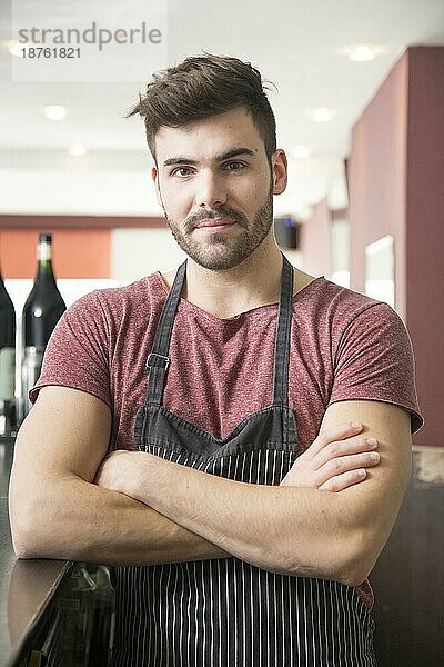 Porträt eines jungen Mannes mit Schürze an einer Bar