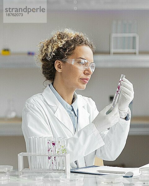 Weibliche Forscherin im Labor mit Reagenzgläsern und Schutzbrille
