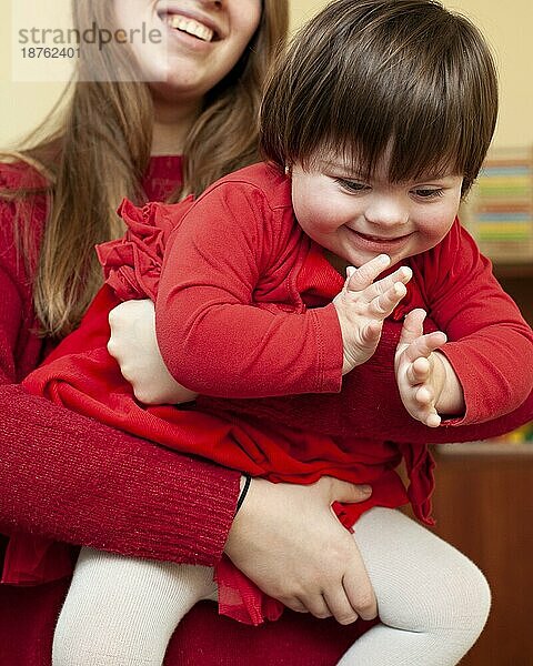 Frau hält glückliches Kind mit Down Syndrom