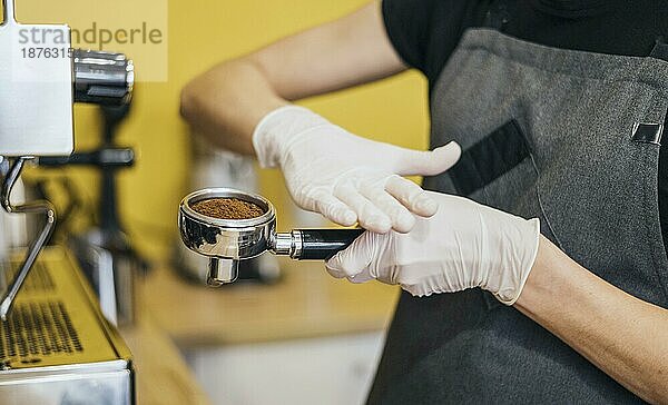 Seitenansicht Barista mit Latexhandschuhen bei der Vorbereitung der Kaffeemaschine. Foto mit hoher Auflösung