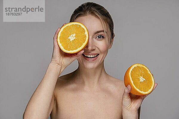 Schöne Frau hält halbierte Orange