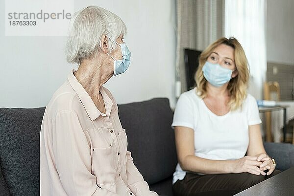 Frau  die ihre Verwandten im Pflegeheim besucht  trägt eine medizinische Maske
