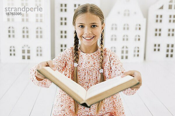 Schönes glückliches Mädchen posiert mit Buch