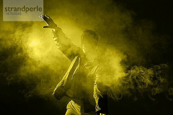 Mann tanzt Rauch mit leuchtendem Licht. Schönes Foto