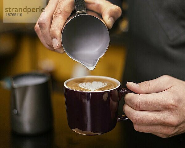 Vorderansicht eines männlichen Barista  der eine Tasse Kaffee einschenkt