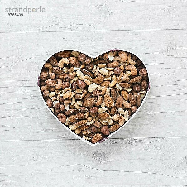 Draufsicht gesunde Trockenfrüchte Herzform Holzschreibtisch. Foto mit hoher Auflösung