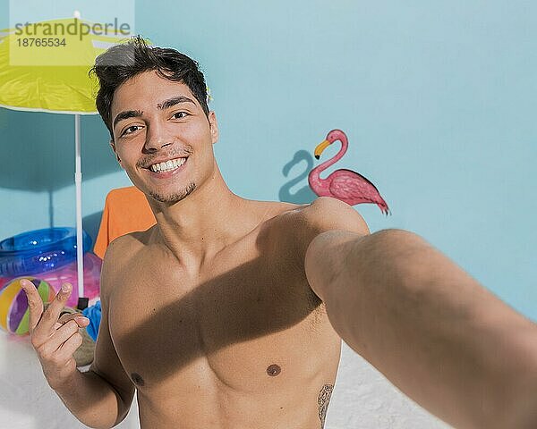 Lächelnder muskulöser Mann am Strand  der ein Selfie macht