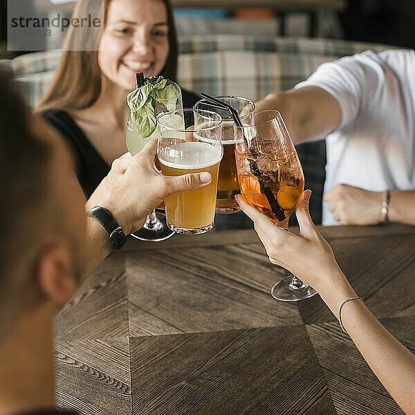 Freunde sitzen an der Bar zusammen und stoßen mit Getränken an