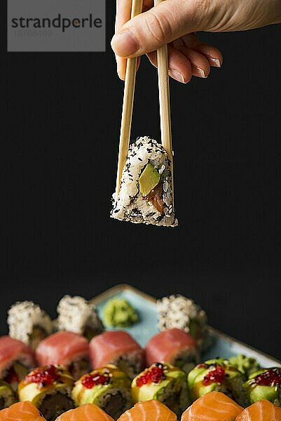 Person hält Sushi mit Stäbchen. Foto mit hoher Auflösung