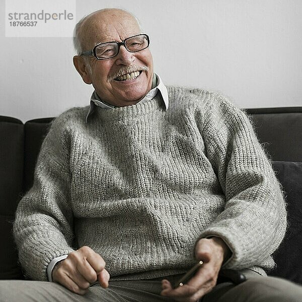 Lächelnder älterer Mann im Pflegeheim mit Smartphone