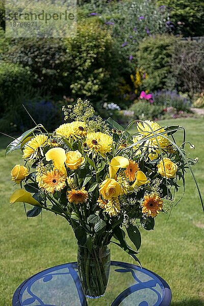 Gelbe Blumen in einer Vase auf einem Gartentisch