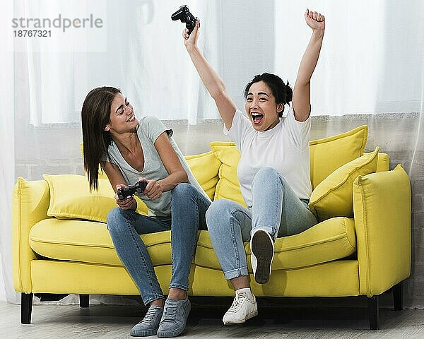 Aufgeregte Frauen spielen zu Hause zusammen Videospiele. Foto mit hoher Auflösung