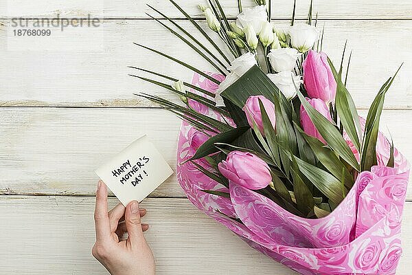 Weibliche Hand mit Urlaubskarte Blumenstrauß