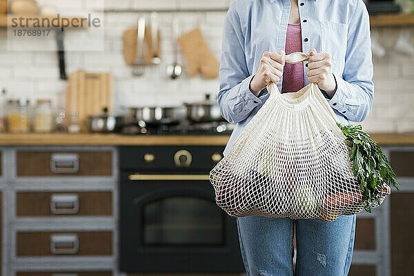 Erwachsene Frau hält wiederverwendbare Tasche mit Bio-Gemüse