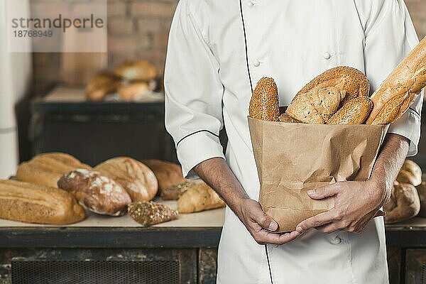 Mitte Abschnitt männlichen Bäcker hält Papiertüte mit Broten. Auflösung und hohe Qualität schönes Foto