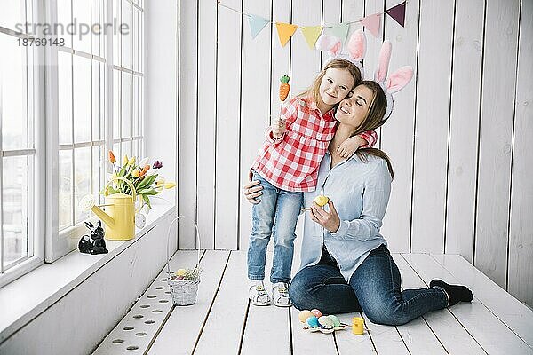 Kleines Mädchen Mutter Hasenohren sitzen mit Ostereiern