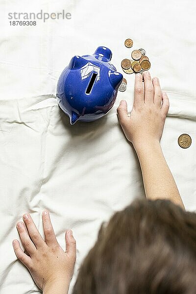 Draufsicht Kind beim Zählen seines Geldes aus dem Sparschwein