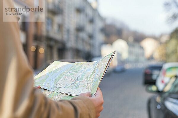 Nahaufnahme eines männlichen Reisenden  der eine Karte in der Hand hält und auf einer Straße steht. Hohe Auflösung Foto