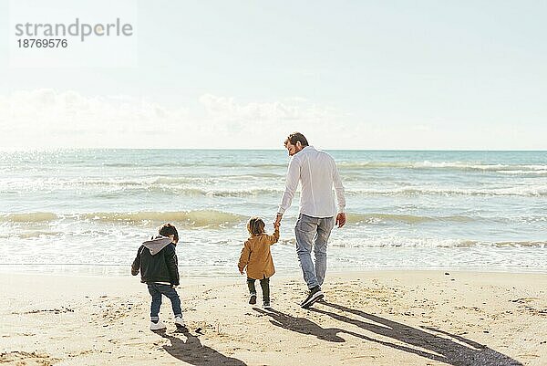 Mann mit Kleinkindern geht Richtung Meer. Schönes Foto