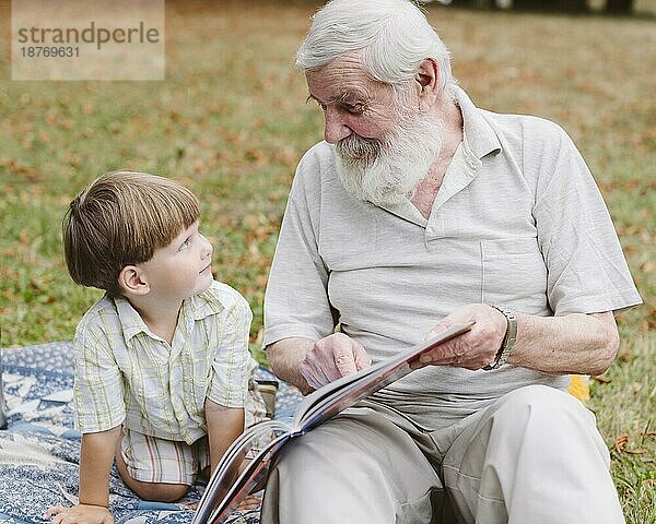 Opa liest dem Enkel im Park vor