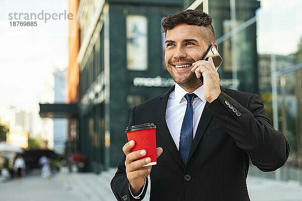 Geschäftsmann im Freien  der seinen Kaffee trinkt und telefoniert