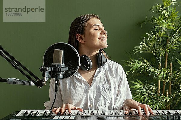 Vorderansicht smiley weibliche Musikerin spielt Klavier Tastatur drinnen