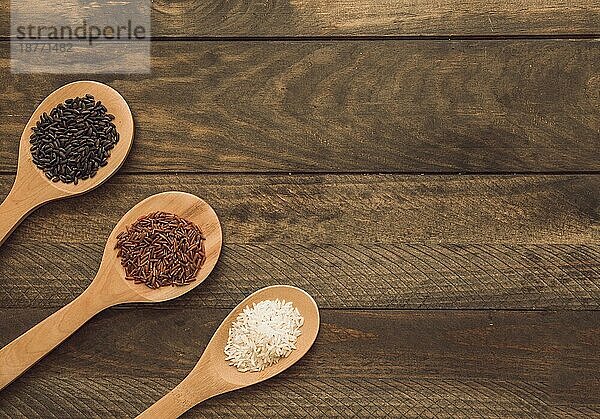 Holzlöffel mit drei verschiedenen Arten von Reiskörnern Holzbrettchen