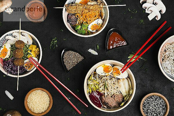 Verschiedene Arten von Ramen-Nudeln nach asiatischer Art mit Reissauce Sesamkörner schwarz strukturierter Hintergrund