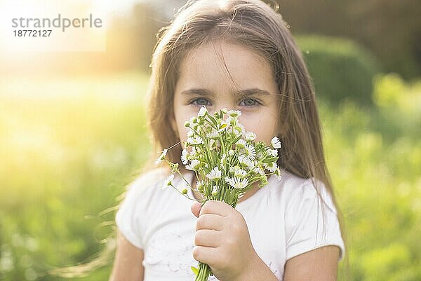 Mädchen riecht an weißen Blumen. Foto mit hoher Auflösung