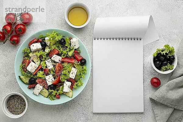 Draufsicht Salat mit Fetakäse  Tomaten und Oliven mit leerem Notizblock. Auflösung und hohe Qualität schönes Foto