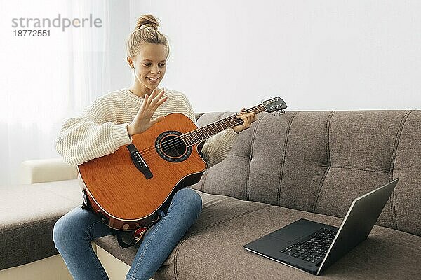 Junges Mädchen spielt Gitarre zu Hause