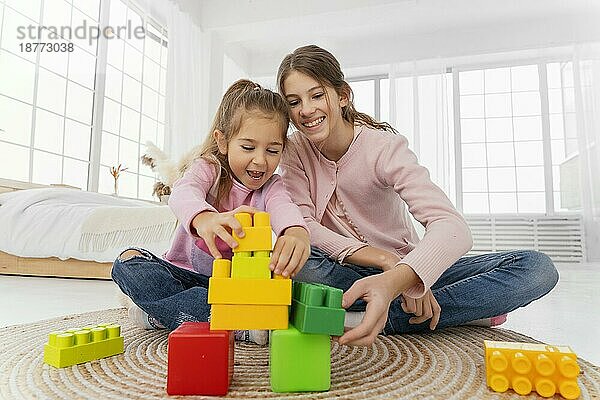 Vorderansicht zwei Schwestern spielen zu Hause Spielzeug. Foto mit hoher Auflösung