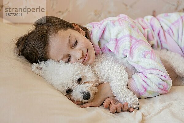 Mädchen umarmt ihr Hundebett beim Schlafen
