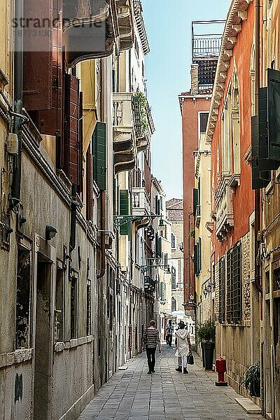 Menschen  die eine enge Straße in Venedig entlanggehen