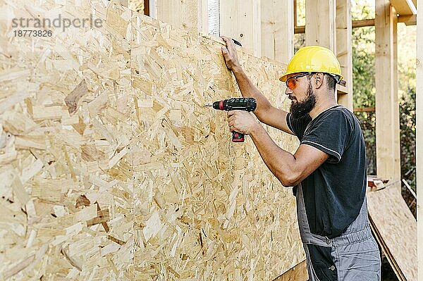Seitenansicht Bauarbeiter beim Bohren von Sperrholz mit Kopierraum