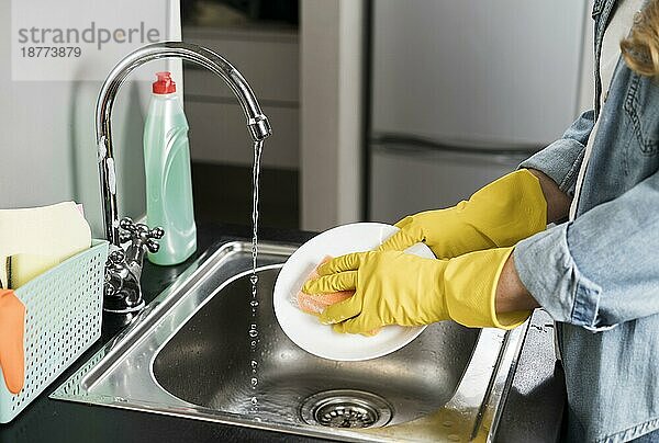 Seitenansicht Frau wäscht Teller Waschbecken. Auflösung und hohe Qualität schönes Foto