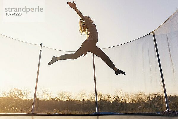 Aktives kleines Mädchen springt Trampolin gegen den Himmel